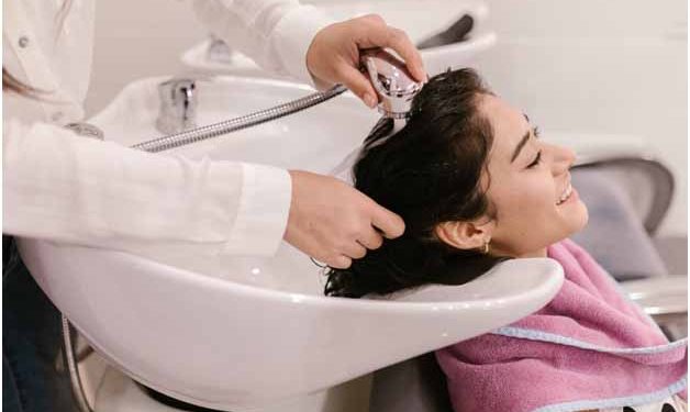 A person washing woman’s hair in a salon