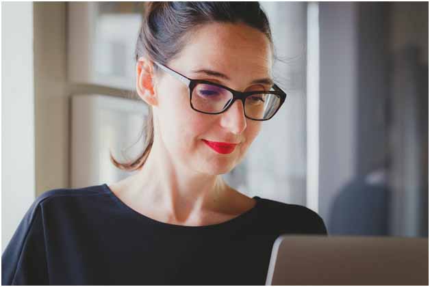 A woman wearing glasses looking at a screen